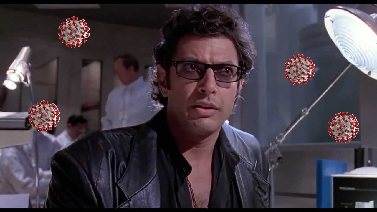 Dr. Malcolm from Jurassic Park sits in the lab surrounded by COVID-19 particles.